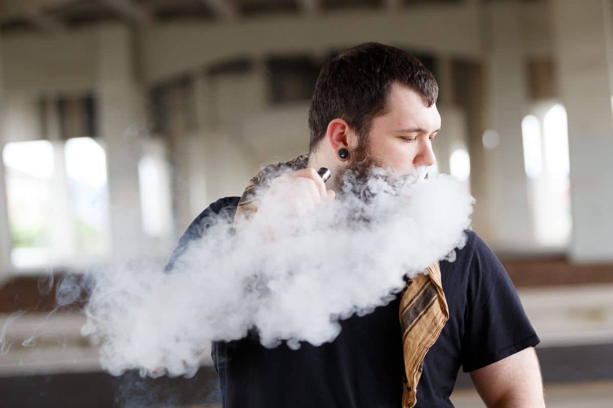 A guy vaping in a parking lot A guy vaping in a parking lot