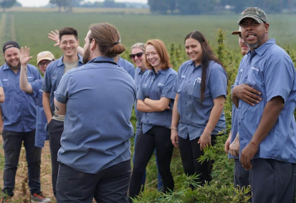 A group of people in blue shirts belonging to "About Us" standing in a field.