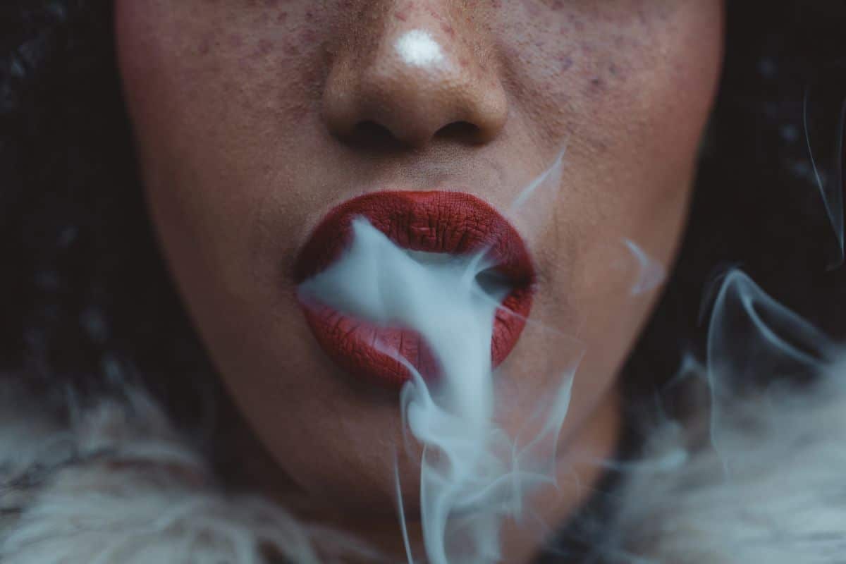 A woman smoking ghost extracts e-cigarette with red lips. A woman smoking ghost extracts e-cigarette with red lips.