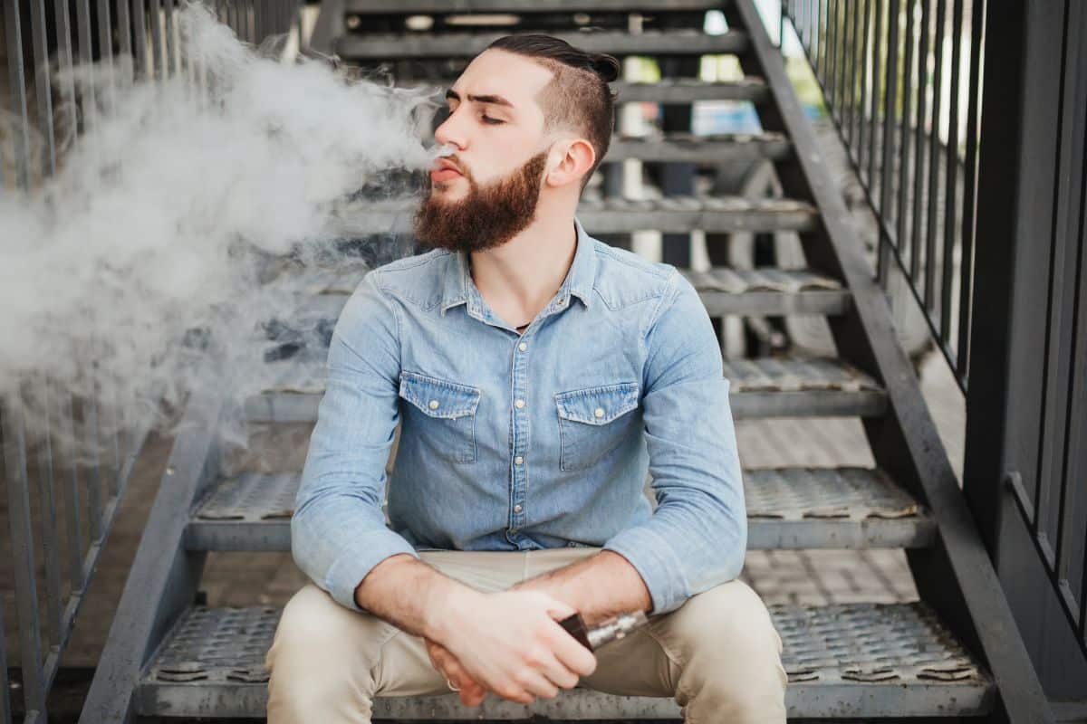 A guy vaping outdoors to deal with his anxiety issues