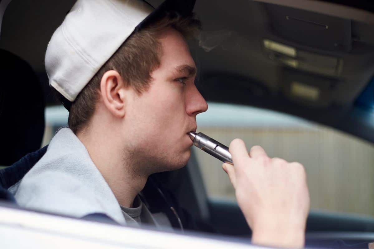 A guy using vaping device inside a car A guy using vaping device inside a car