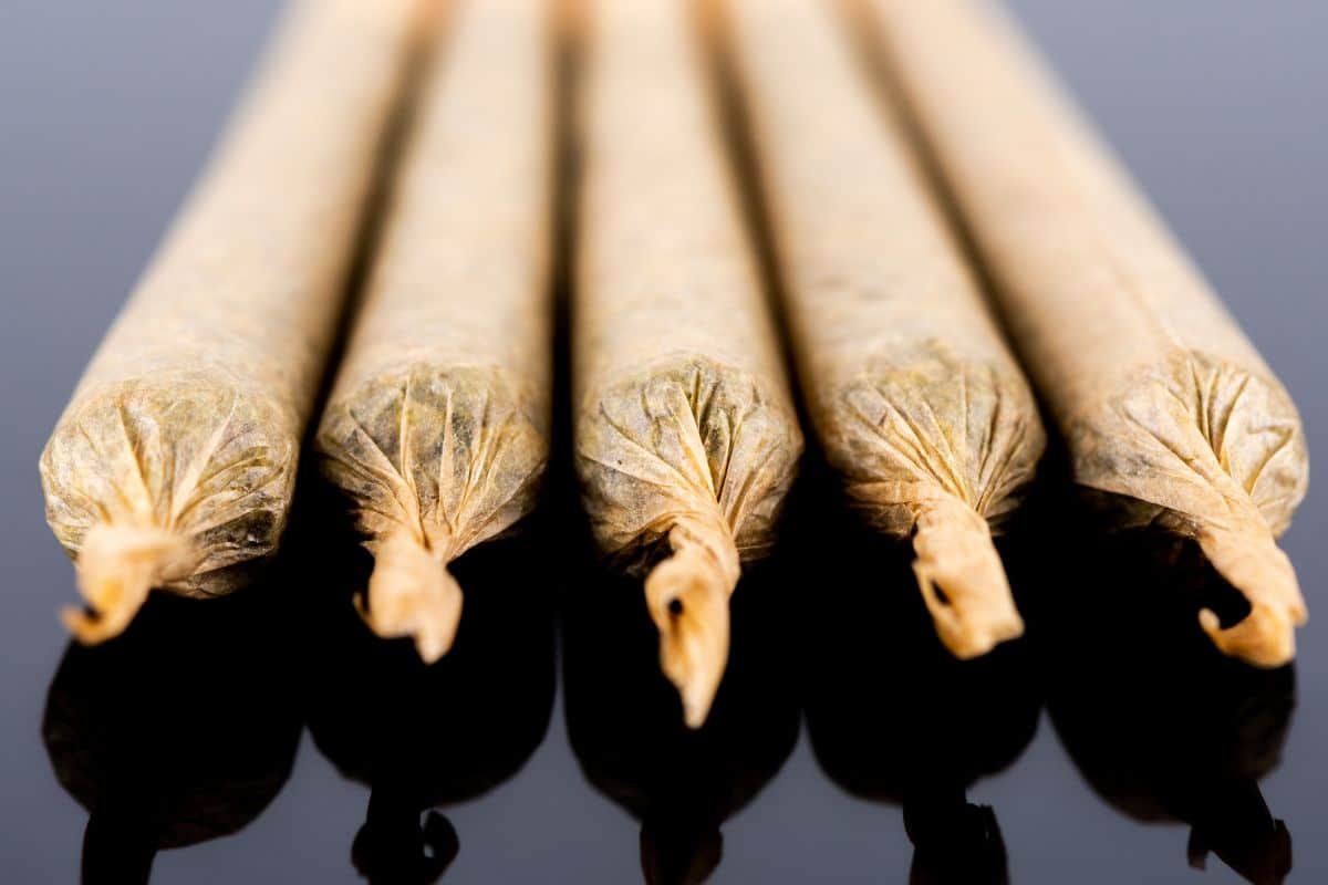 A collection of marijuana sticks arranged on a black surface, showcasing some creative weed smoking tricks.