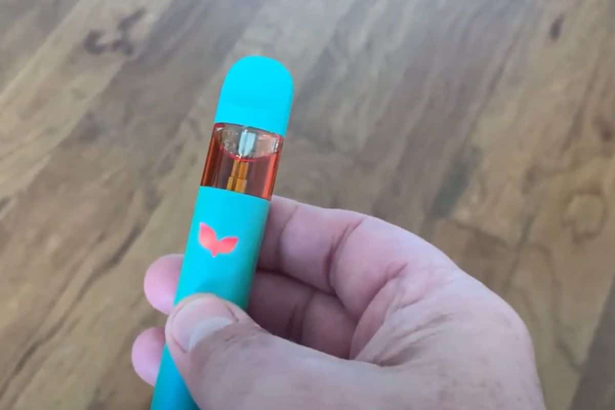 A person holding a blue vaporizer known as the "Urb vape", demonstrating how to turn it on.