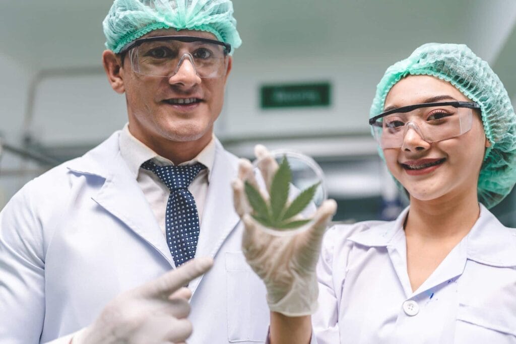 Two people in lab coats holding a cannabis leaf, discussing the legal status of THCa in Indiana.