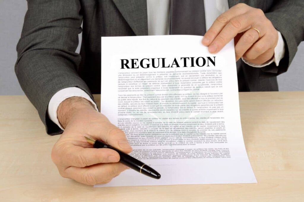 A man in a suit is holding up a piece of paper with the word regulation on it, while pondering whether THCa is legal in California.