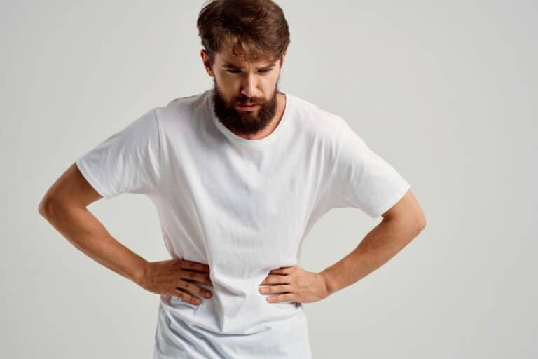 A bearded man with his hands on his stomach wonders if delta 9 gummies help with stomach pain.