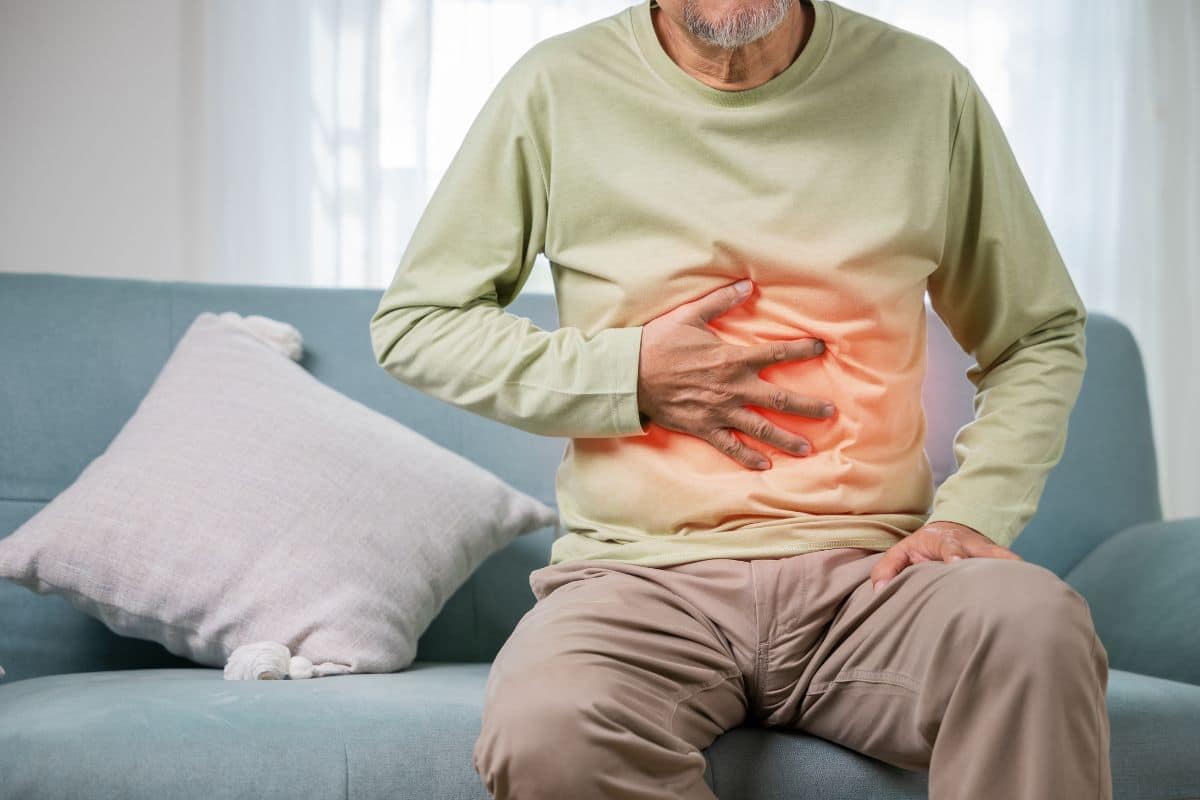A man sitting on a couch with his stomach hurting wonders if delta 8 could help with his nausea.