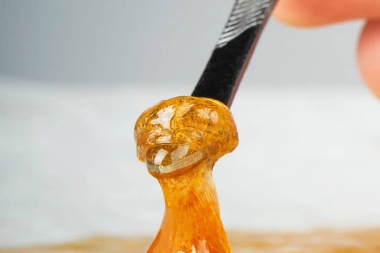 A person is dipping a spoon into a bowl of CBD terp sauce.
