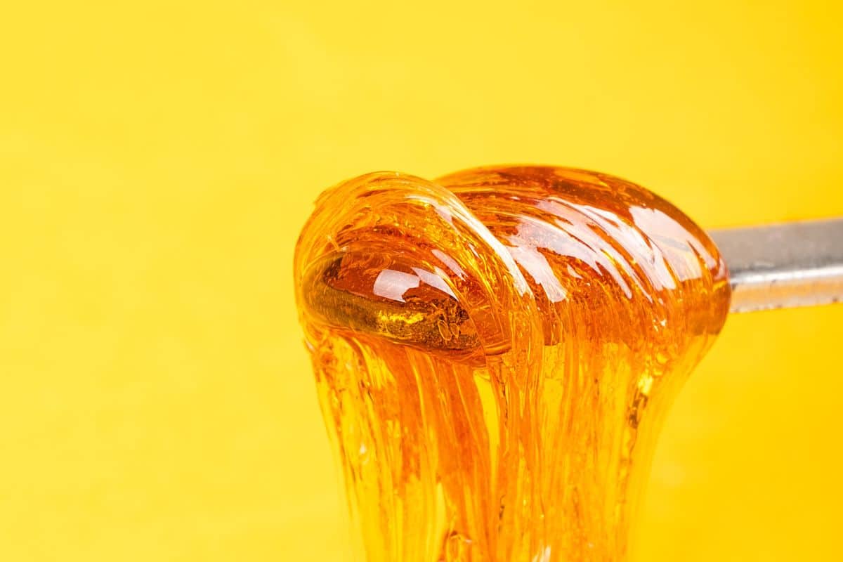 CRC Wax drips from a spoon on a yellow background.