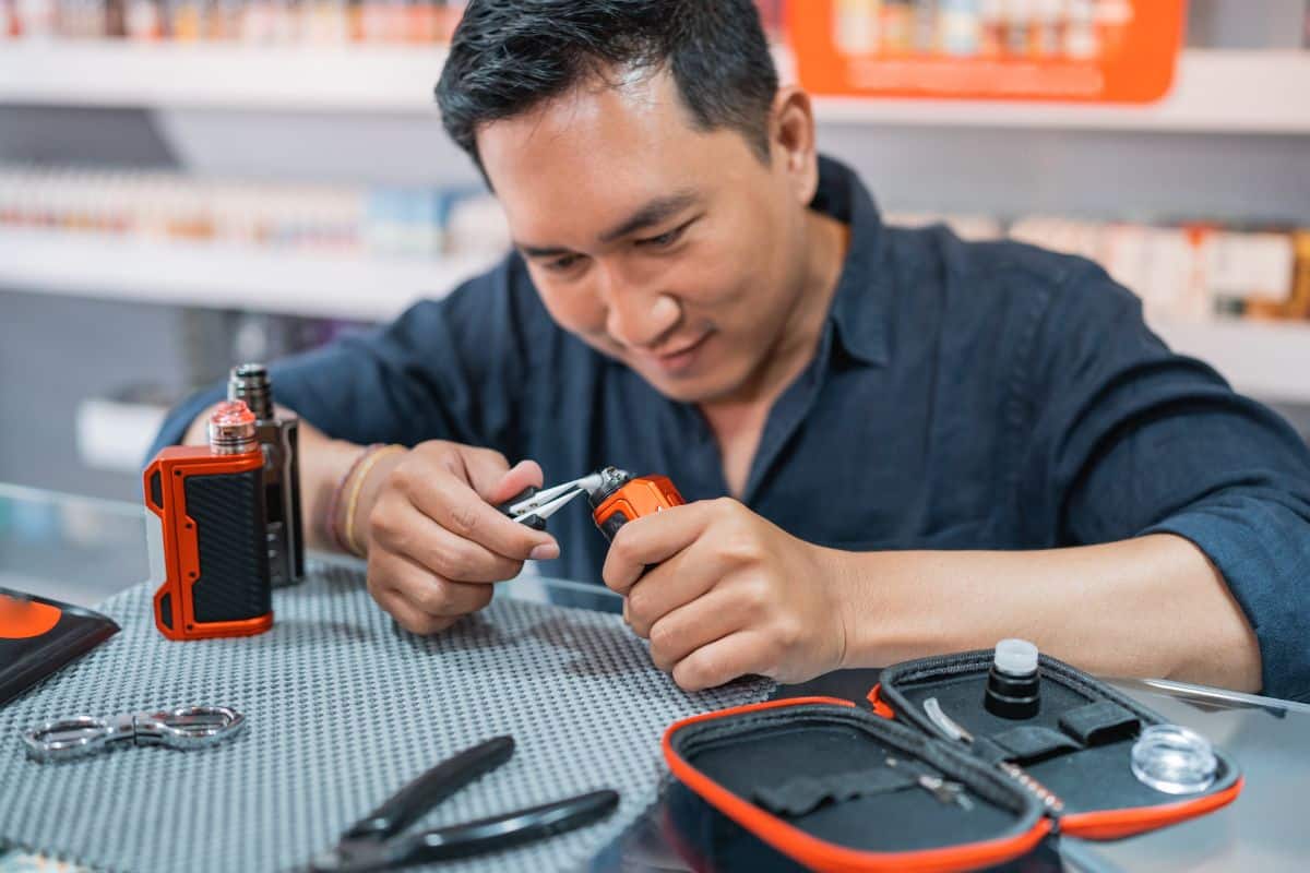 Man repairing a vape that keeps hitting after use at a workbench.