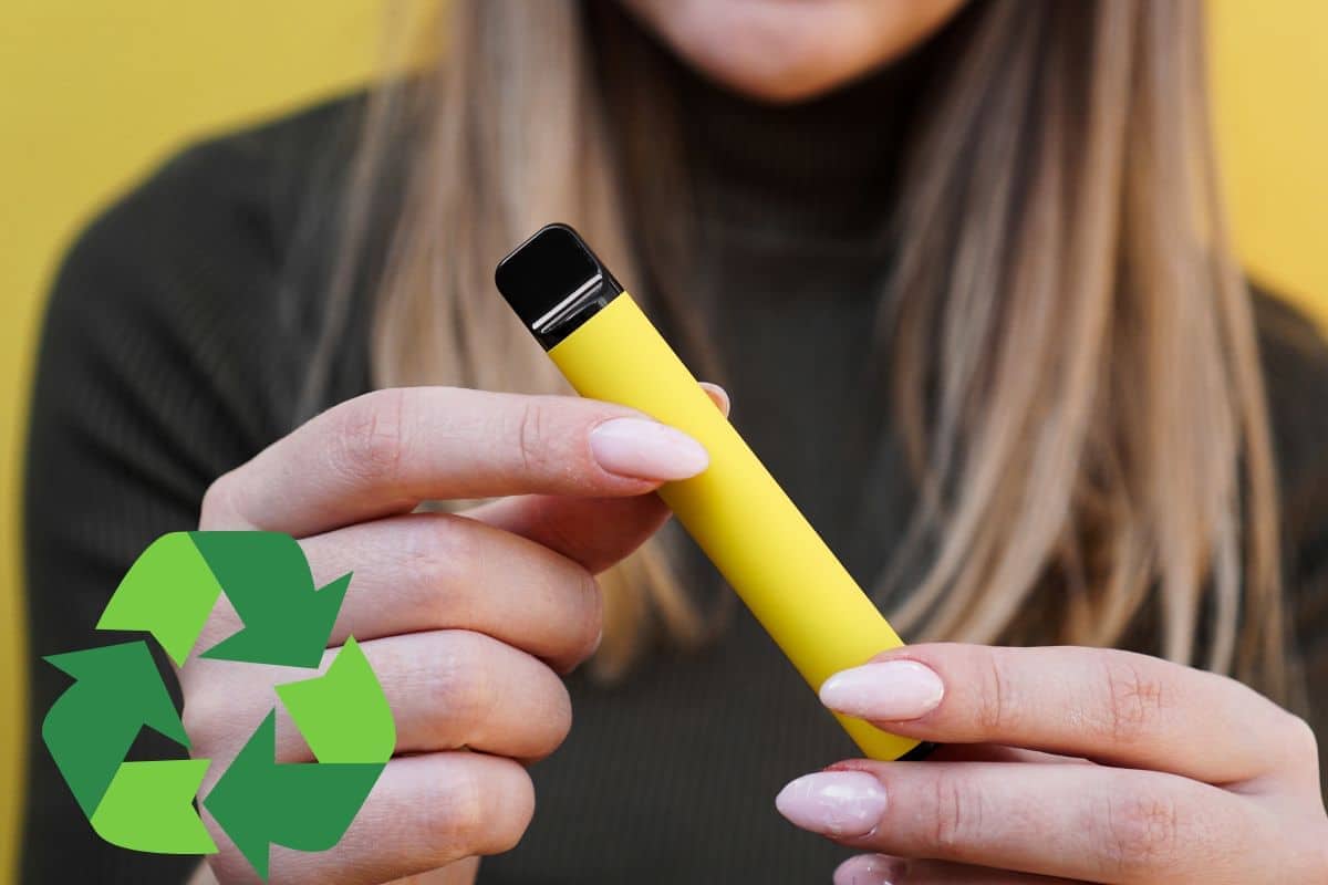 Woman holding an electronic device with a recycling symbol, implying how to recycle disposable vapes.