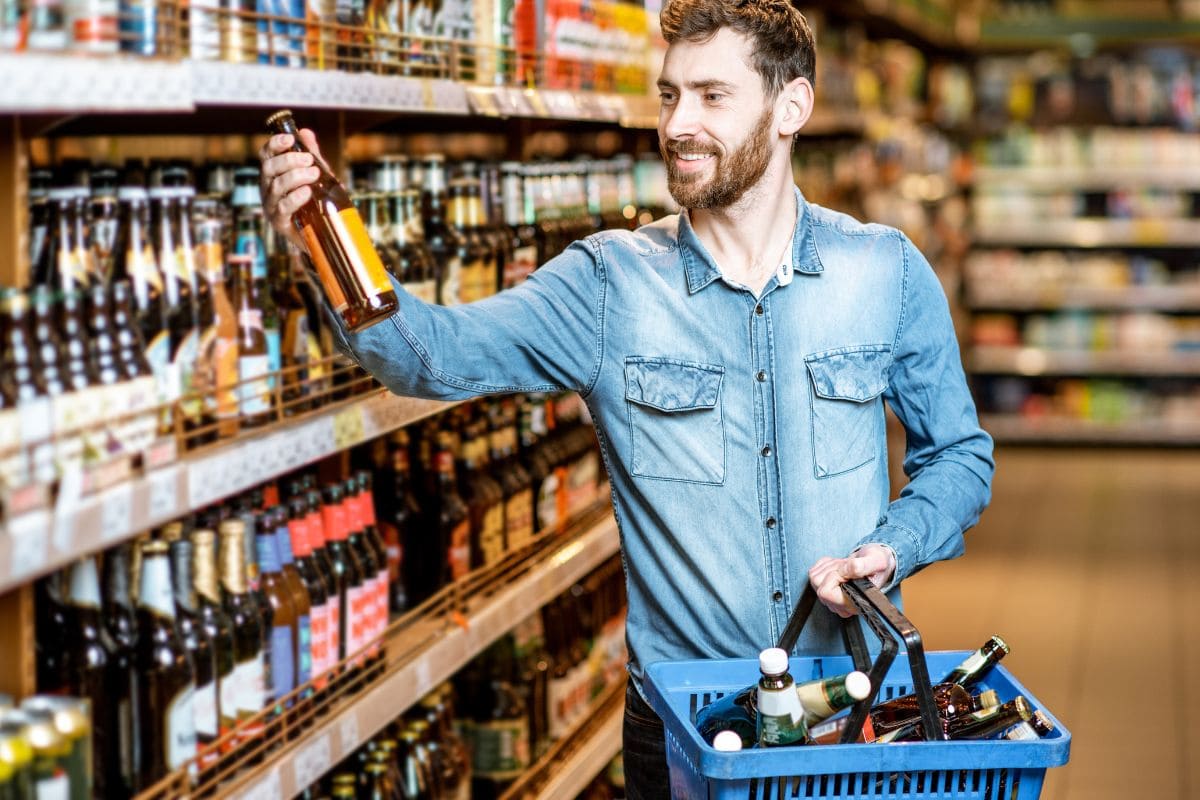 A man is selecting wine and beer from a shop