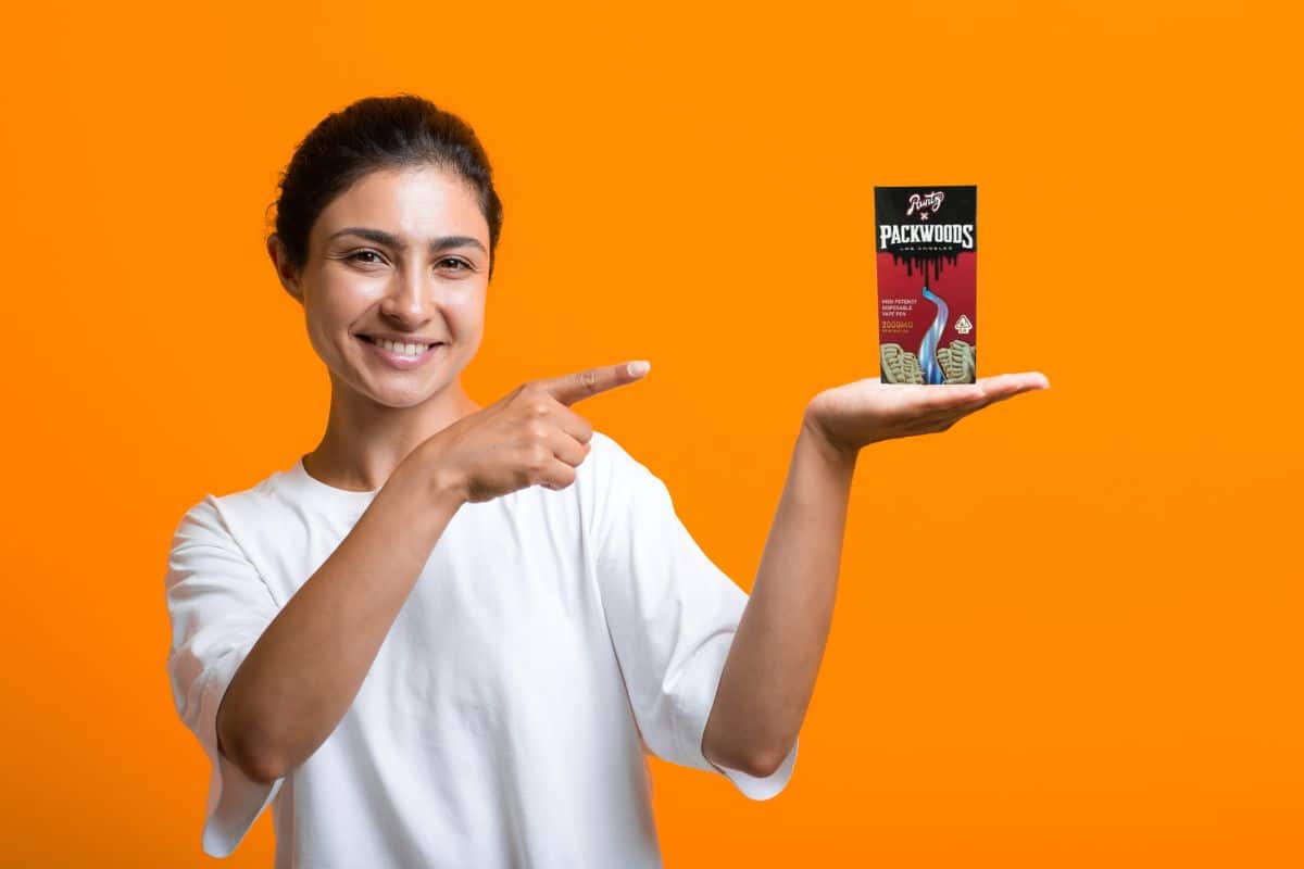 A lady holding a pack wood vape pen