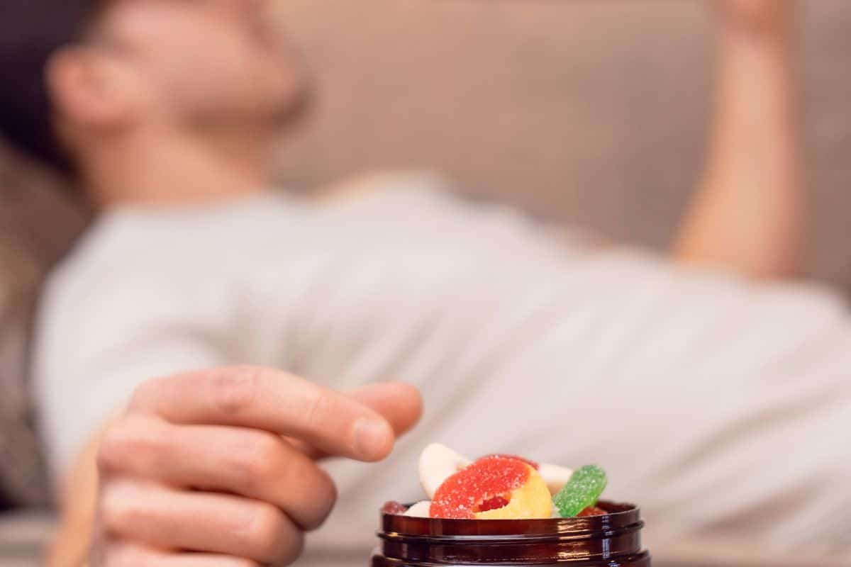 Selective focus on a person's hand reaching for colorful Diamond Shruumz candies from a small bowl.