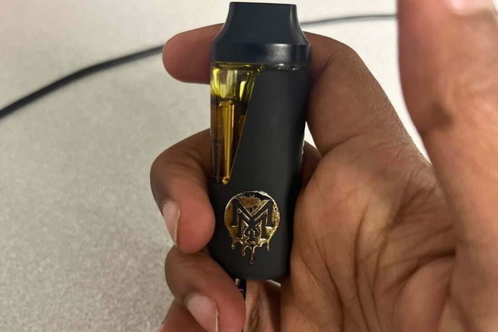 A person charging Muha Meds vape with the help of a cable