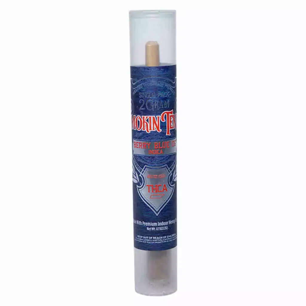 A cylindrical container features a dark blue label with red and white text reading Smokin Tenns THCa Pre-Roll 2g - Berry Blue OG. It has transparent sections at the top and bottom, revealing a wooden tip inside.