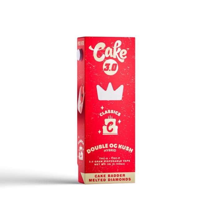 Red and white rectangular box labeled Cake 3.0, adorned with a crown logo, highlights the Double OG Kush Hybrid. The packaging, part of the Cake Classics range, features Cake Badder Melted Diamonds and a small graphic symbolizing a disposable vape pen.