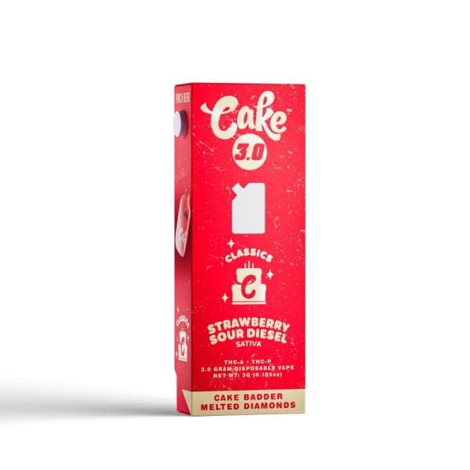 The red box packaging for Cake Classics Cake 3.0 highlights the Strawberry Sour Diesel Sativa vape. It contains THC-A + THC-P, with 2.0 grams of potency. The front showcases a white cut-out shape and brand logo, mentioning Cake Badder Melted Diamonds.
