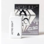 A sleek white vape device labeled Astro Eight stands in front of its packaging. The box features a geometric design in black and white tones with the same Astro Eight branding, highlighting its Galaxy Goo Sativa blend.