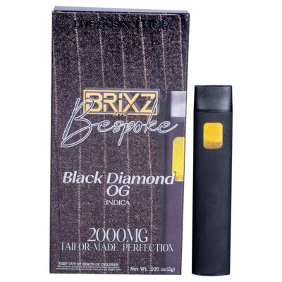 A black and yellow vape pen stands next to a tall box elegantly labeled: BRIXZ NYC Bespoke, Black Diamond OG, Indica, 2000MG, Tailor Made Perfection. A rich brown pattern graces the background of this BRIXZ NYC Bespoke THCP Disposable 2g delight.