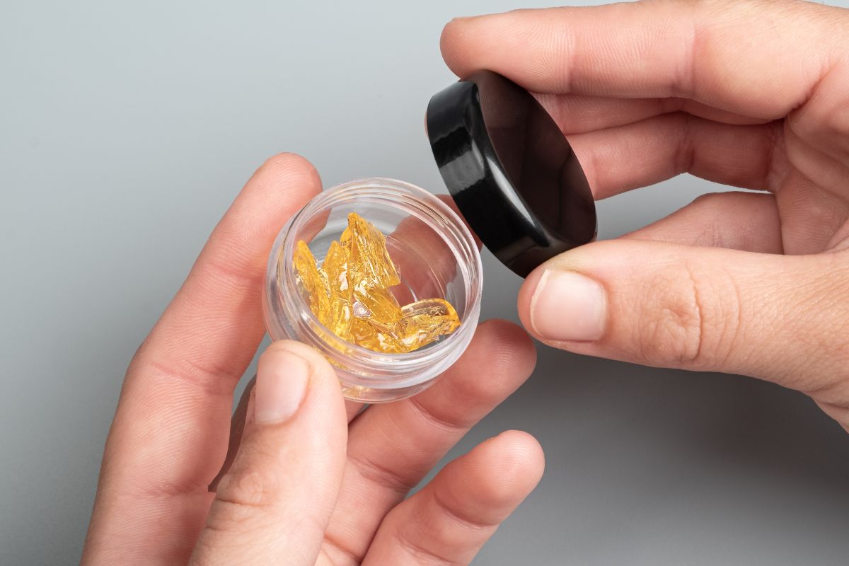 A man holding a jar containing high-terpene cannabis extract