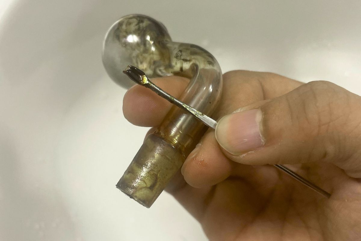 A person extracting dab reclaim from a dabbing rig