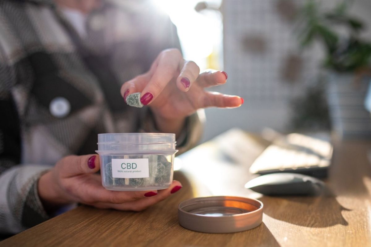 A lady eating live rosin gummies from an airtight jar to keep them fresh