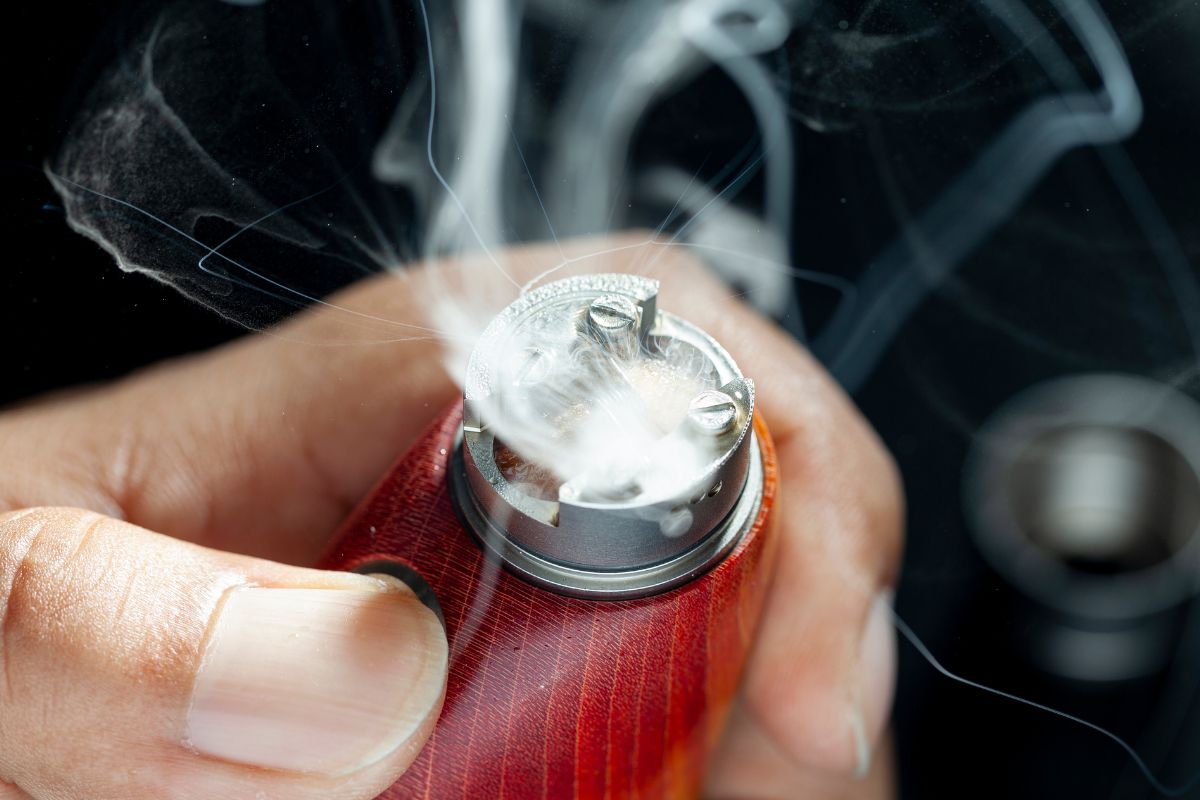 A person holding a vape popping and spitting back