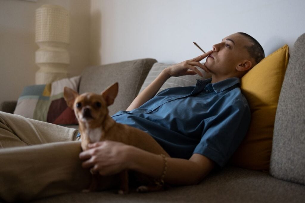 A person smoking weed while relaxing with his dog