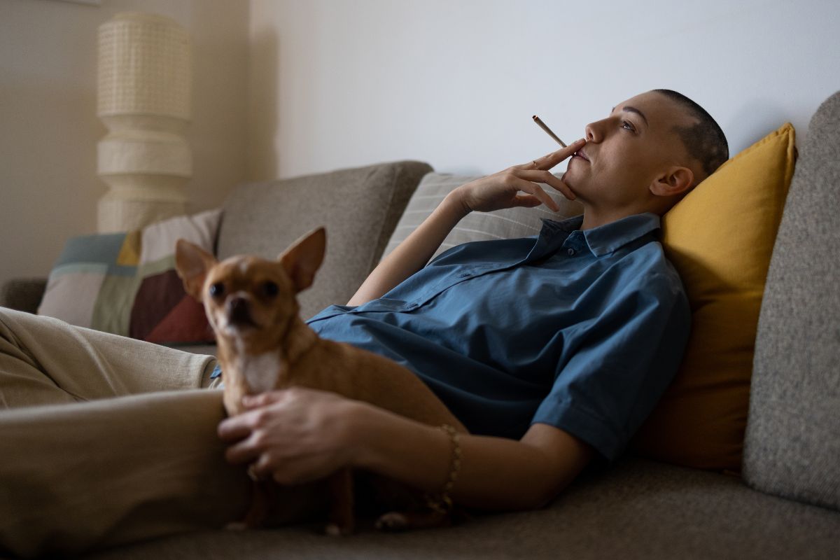 A person smoking weed while relaxing with his dog