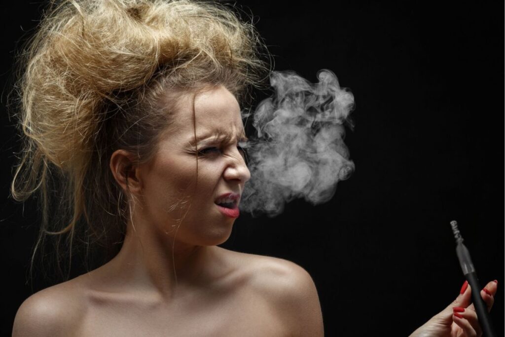 A lady is coughing while using a vape cart