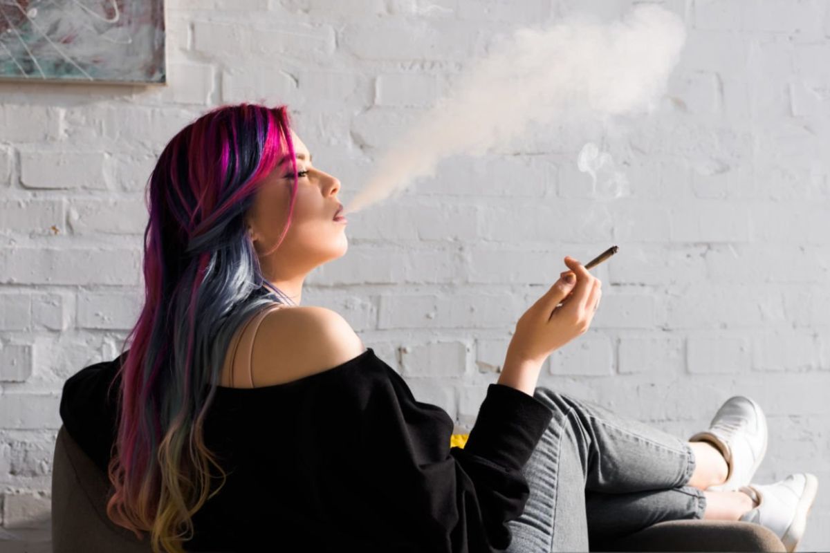 A lady smoking cannabis and relaxing on the couch