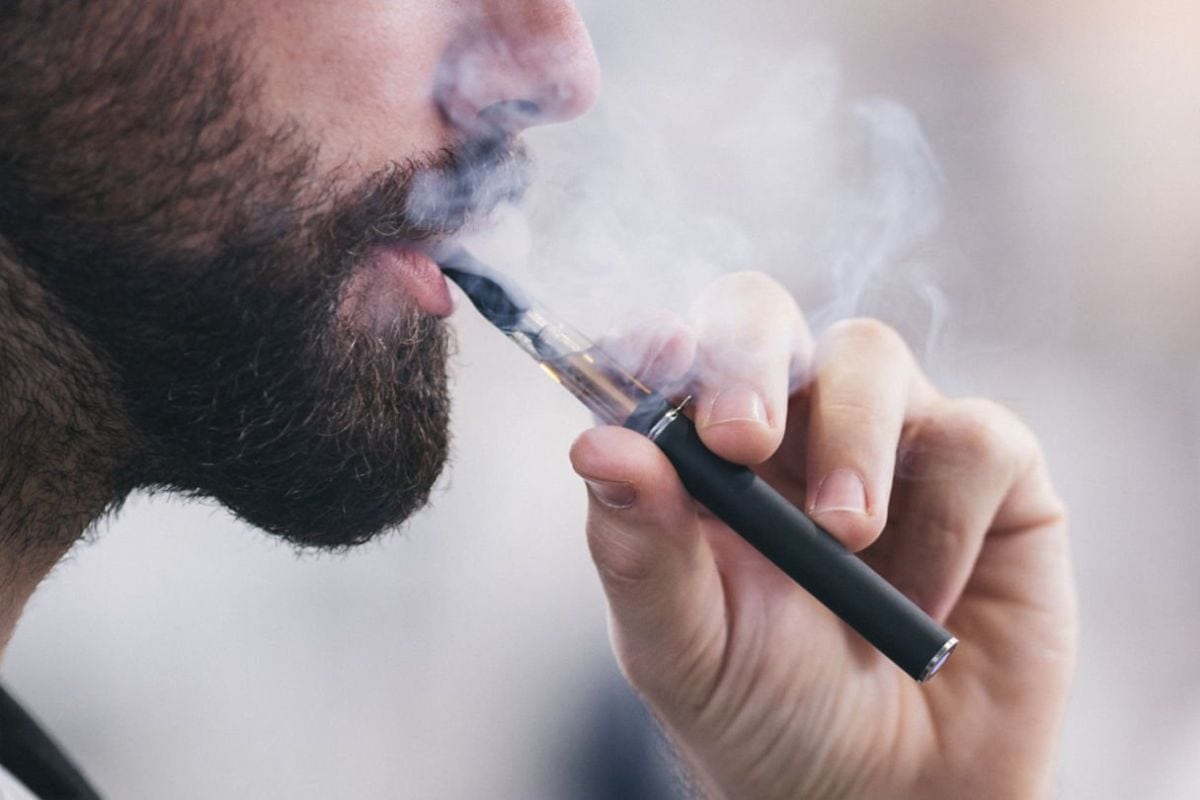 A person inhaling from a vape cartridge device
