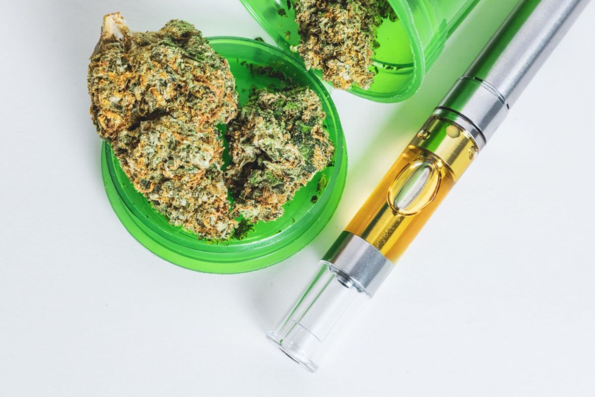 A collection of cannabis buds placed alongside a vape cartridge