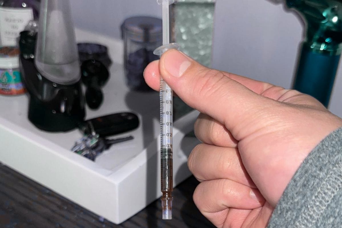 A person is holding RSO concentrate for dabbing