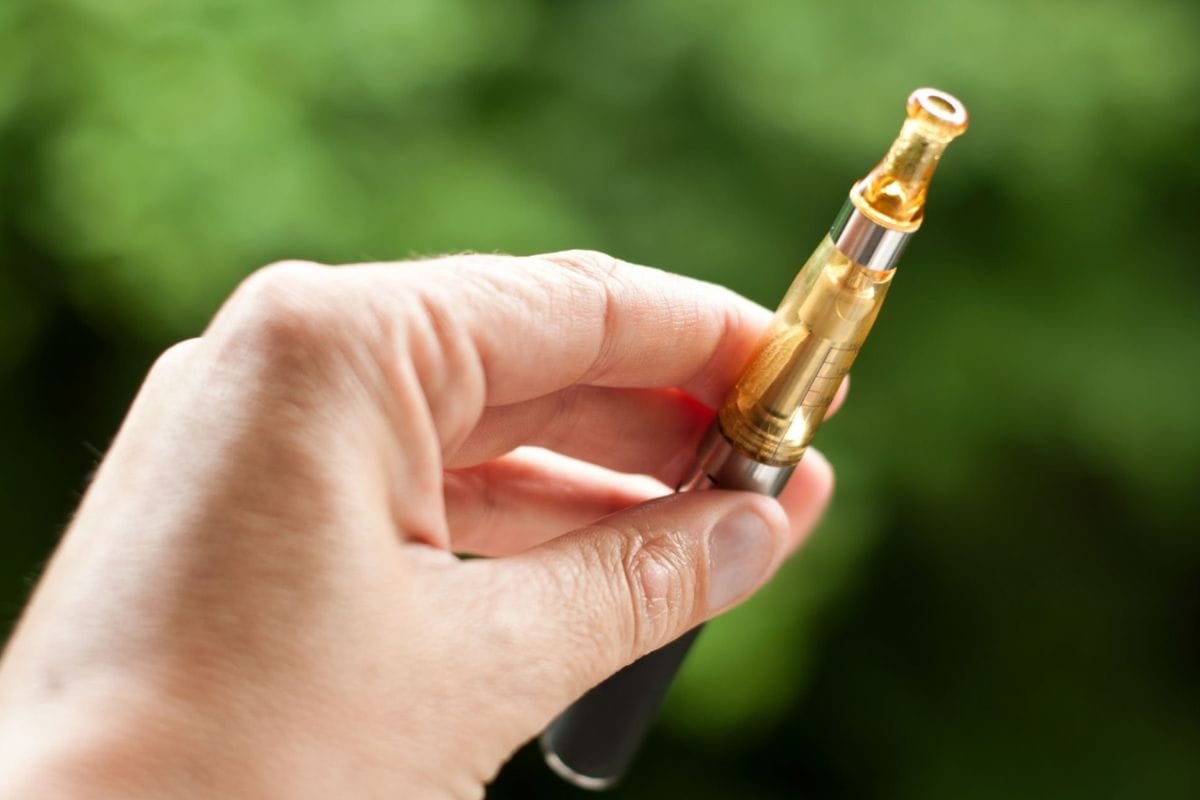 A person demonstrating how to preheat a vape cartridge